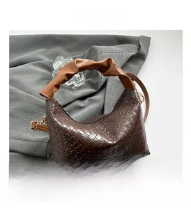 Detail of dark brown woven texture handbag with pleated handle and gold hardware detail