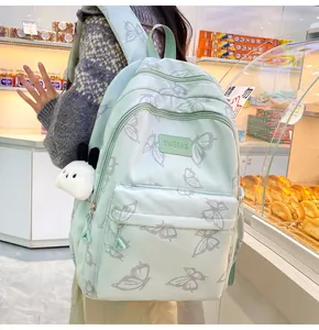 Detalle de la mochila verde claro con estampado de mariposas y peluche de panda