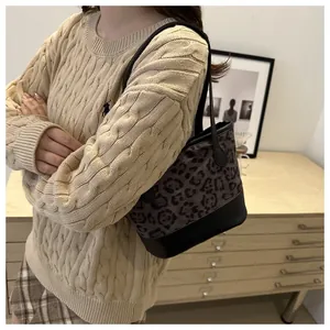 Close-up of stylish leopard print bucket bag with black leather trim and shoulder strap