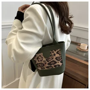 Green leather bucket bag with leopard print panel detail shown on a female model