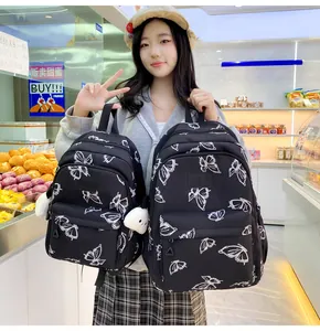 Detalle de mochila negra con estampados de mariposas y llavero de muñeco de peluche