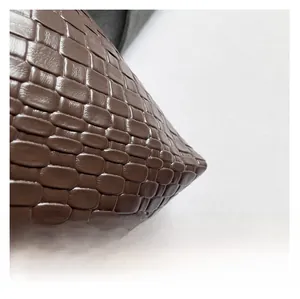 Detailed macro view showing the brown woven leather texture and craftsmanship of the bag