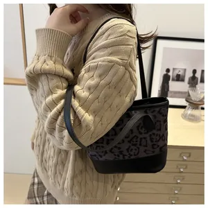 Detail view of stylish leopard print bucket bag featuring black straps and a sturdy base
