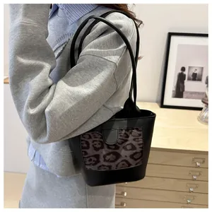 Detail view of a vintage black tote bag with leopard print panel on female model