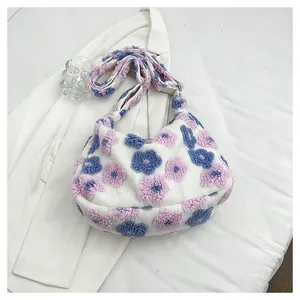 Detailed view of plush floral tote bag with blue and purple flowers on soft white fabric