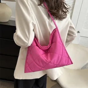 Quilted pink crossbody bag with a diamond lattice pattern and a minimalist aesthetic