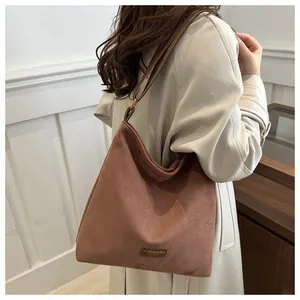 Detailed close-up of dark brown suede tote bag featuring a metallic fashion label