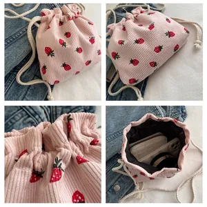 Detail view of pink corduroy drawstring bag interior with red strawberry pattern and white rope