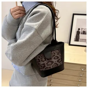 Modern shoulder bag with leopard print panel worn by a model in a cozy interior setting