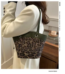 Detail of leopard print tote bag with dark green leather handles and metal eyelets
