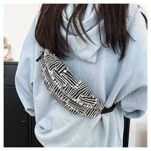 Close-up of a striped canvas chest bag with adjustable strap worn by a model in a casual setting