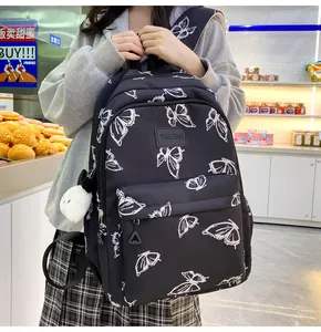 Detalle de mochila negra con estampados de mariposas, peluche de panda y logo de cuero