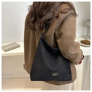 Detail of black suede hobo bag with adjustable wide shoulder strap and metal hardware