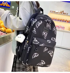 Detalle de mochila negra con estampado de mariposas blancas y colgante de panda