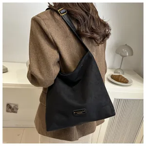 Detail of minimalist black tote bag featuring gold buckle and leather fashion label