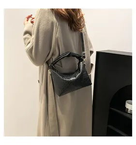 Detail of black woven shoulder bag featuring a knotted handle and adjustable strap