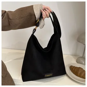 Detail of black suede tote bag showing gold buckle and A beautiful FASHION embossed label
