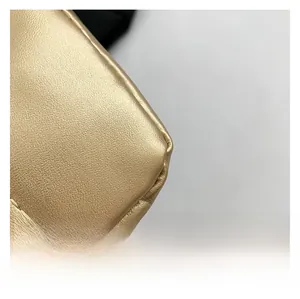 Close-up of golden leather shoulder bag with fine stitching and litchi grain texture