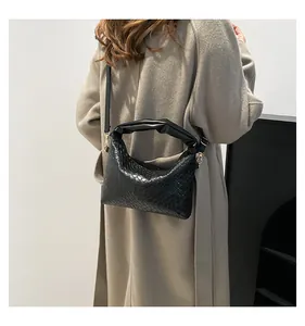 Close-up of black woven leather handbag with pleated handle and golden metal hardware