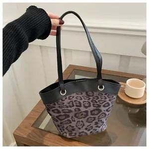Close-up of leopard print fabric detail and black leather stitching on a tote bag