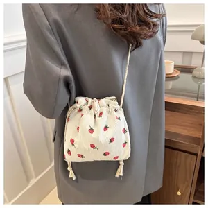 Detailed view of beige corduroy mini bucket bag with red strawberry embroidery patterns