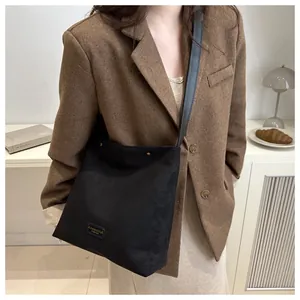 Detail of minimalist black matte tote bag with logo label and stylish crossbody strap