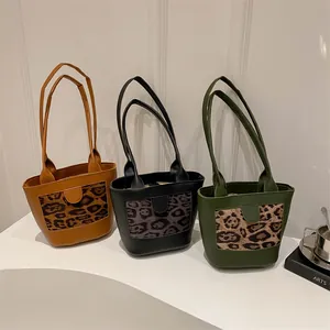 Three elegant leopard print tote bags in tan, black, and green arranged on a white display