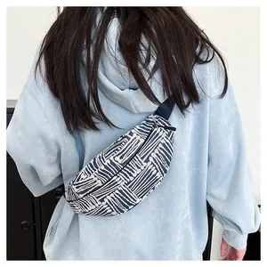 Detail view of blue geometric canvas crossbody bag worn over a light blue hoodie