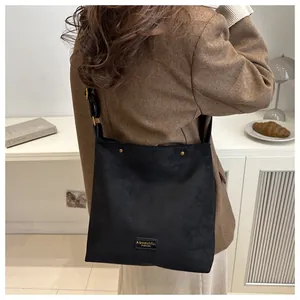 Detail of black suede tote bag featuring metallic rivets and fashion brand label tag