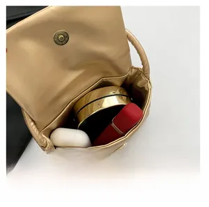 Internal capacity of the gold mini square bag showing space for earphones and lipstick