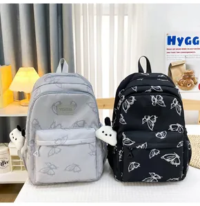 Detalle de mochilas con estampado de mariposas en gris y negro con llavero de panda suave