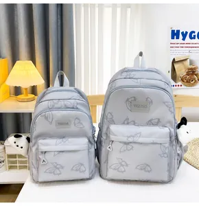 Detalle de dos mochilas grises con estampado de mariposas y colgantes de panda