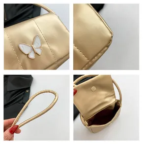Close-up of gold PU leather handbag with butterfly ornament and magnetic clasp detail