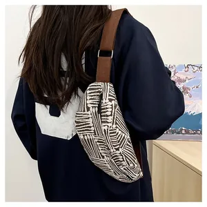 Detail of canvas chest bag featuring brown and white stripes with adjustable strap