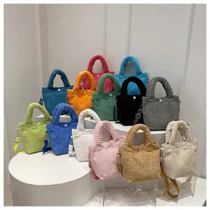 Collection of colorful corduroy crossbody bags arranged on white tiered display stands