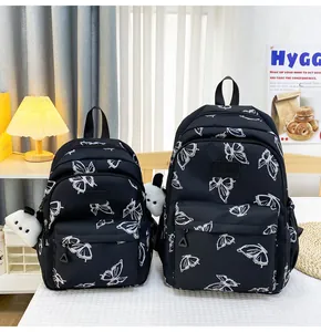 Detalle de mochilas negras con estampado de mariposas en dos tamaños y colgante de panda