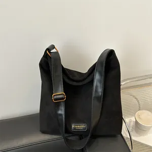 Minimalist black matte suede tote bag with leather strap and gold buckle on a bench