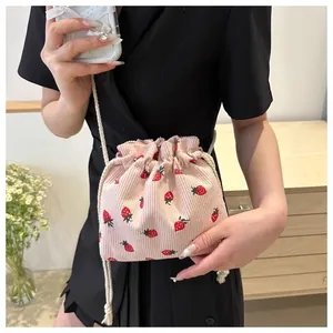 Detailed close-up of pink corduroy mini bucket bag with red strawberry pattern
