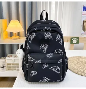 Detalle de la mochila de nylon negro con estampados de mariposas y colgante de panda