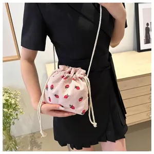 Detailed close-up of pink corduroy bucket bag with cute strawberry pattern and drawstring
