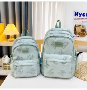 Detalle de mochilas verde menta con estampado de mariposas en dos tamaños con adornos