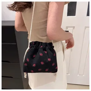 Detail of black corduroy drawstring bucket bag with cute red strawberry patterns
