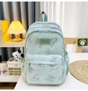 Detalle de la mochila verde menta con estampado de mariposas y bolsillo frontal