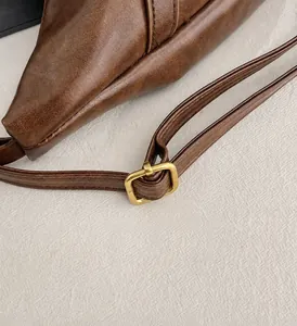 Primer plano de la hebilla dorada ajustable en la correa de cuero marrón con costuras finas