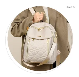 Dettaglio di zaino in nylon beige con motivo trapuntato e finiture in metallo oro