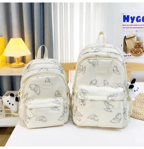 Mochilas de nailon crema en dos tamaños con estampado de mariposas y colgante de panda