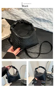 Detail view of black woven texture shoulder bag with stylish ruched handle and metal clasp