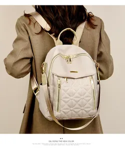 Vista dettagliata dello zaino in nylon trapuntato beige indossato da una modella in blazer