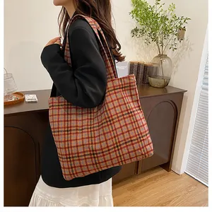 Detail of multi-color plaid tote bag with wide shoulder strap worn with black blazer