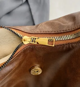 Detalle macro del bolso de cuero vintage marrón con cremallera dorada y cierre magnético